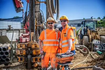 Zwei Kollegen von Bauer Umwelt auf einer Baustelle bei Sonnenschein