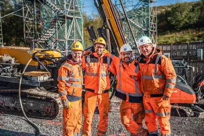 Kollegen von Spesa lächeln auf der Baustelle in die Kamera